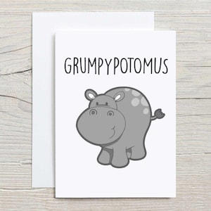 May include: A greeting card featuring a cartoon hippo. The hippo is grey with a lighter grey belly and spots. The text "GRUMPYPOTOMUS" is above the hippo in black letters. The card is set against a white background.