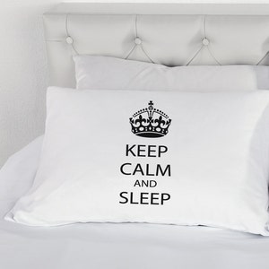 Op de afbeelding: Wit kussensloop met een zwarte kroon en de tekst "Keep Calm and Sleep".