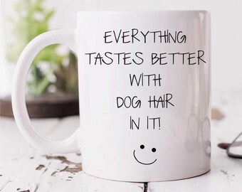 May include: White ceramic coffee mug with a black handwritten saying "Everything tastes better with dog hair in it!" and a smiley face.