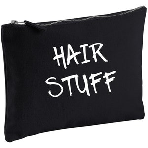 Op de afbeelding: Zwarte canvas toilettas met witte handgeschreven tekst die "HAIR STUFF" zegt.