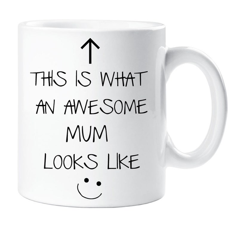 May include: White ceramic mug with black text that reads "This is what an awesome mum looks like" with an arrow pointing up and a smiley face at the bottom.