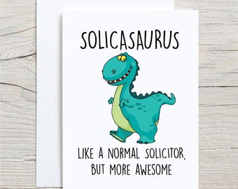 Op de afbeelding: Witte wenskaart met een cartoon dinosaurus in groen en blauw. De tekst "SOLICASAURUS" staat bovenaan, met de tekst "LIKE A NORMAL SOLICITOR, BUT MORE AWESOME" eronder.