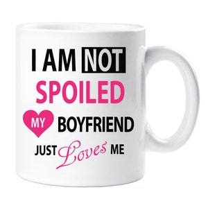 May include: White ceramic mug with black text that reads "I am not spoiled my boyfriend just loves me". The text "spoiled" is in pink and there is a pink heart with the word "my" inside.