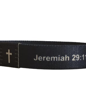 May include: Black woven wristband with a white cross and the text "Jeremiah 29:11..."