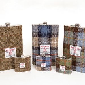 Puede incluir: Cinco matraces de acero inoxidable con diferentes cubiertas de tela Harris Tweed. Los matraces son de varios tamaños y presentan un patrón de cuadros en tonos de marrón, azul, verde y naranja.