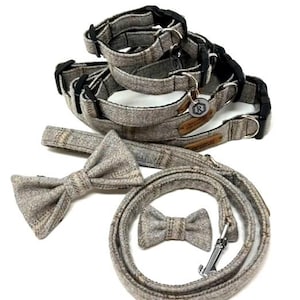 Può includere: Un set di tre collari per cani in tweed grigio, un guinzaglio abbinato e due papillon. I collari hanno fibbie nere e il guinzaglio ha un gancio argentato.