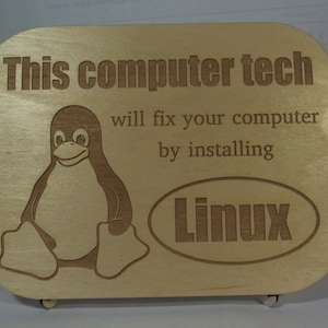May include: A wooden plaque with the text "This computer tech will fix your computer by installing Linux" and a cartoon penguin. The text "Linux" is in a circle.