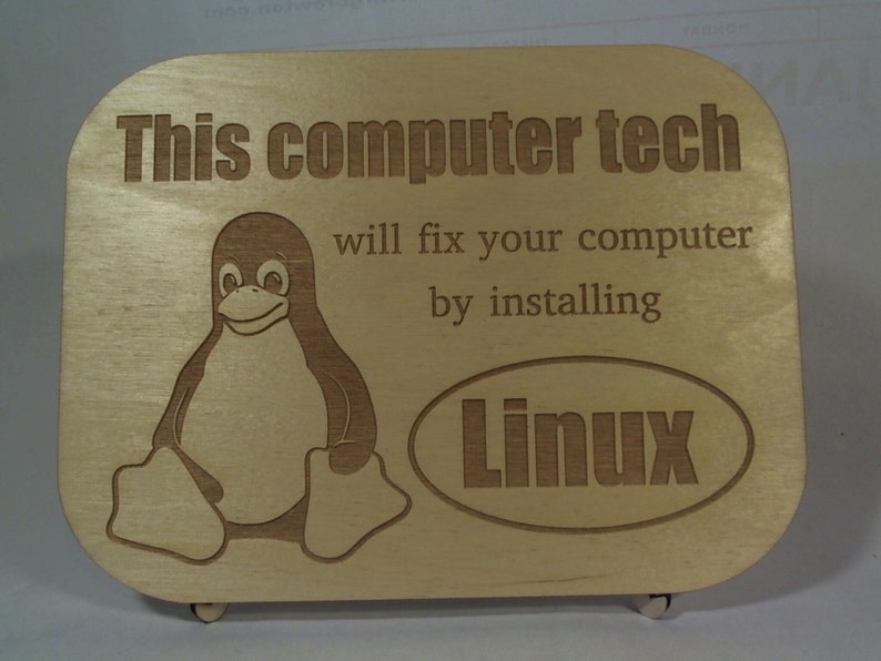 May include: A wooden plaque with the text "This computer tech will fix your computer by installing Linux" and a cartoon penguin. The text "Linux" is in a circle.
