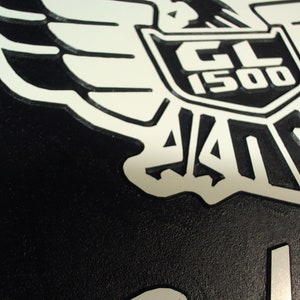 Peut inclure: Embl&egrave;me de moto noir et blanc avec un design d'aigle stylis&eacute; et le texte "GL 1500" dans un bouclier.