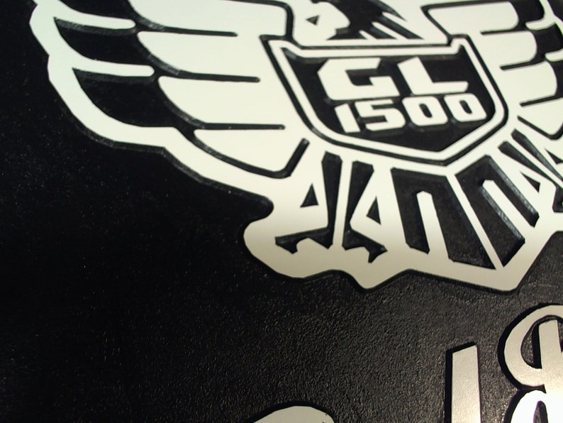 Peut inclure: Embl&egrave;me de moto noir et blanc avec un design d'aigle stylis&eacute; et le texte "GL 1500" dans un bouclier.
