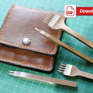 Op de afbeelding: Vier lederbewerkingstools, waaronder een naald voor het stikken en drie verschillende ponsen, liggen op een groene snijmat. De tools bevinden zich in een bruine leren etui met een drukknopsluiting. De etui heeft oranje stiksels langs de randen. De afbeelding bevat de tekst "Download" en een PDF-pictogram.