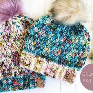 Puede incluir: Dos gorros de ganchillo coloridos con pompones. Los gorros están hechos con una variedad de colores, incluyendo azul, verde, rosa y blanco. Los gorros están sobre una superficie blanca. CROCHET PATTERN está escrito en rosa sobre un fondo blanco.