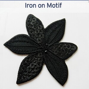 May include: Black iron-on flower motif with a delicate lace design and black rhinestones in the centre.