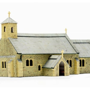 May include: A detailed model church with a stone facade and a grey tiled roof. The building has a small tower with a cross and arched windows. A small porch with a cross is also visible.