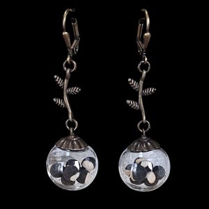 May include: A pair of dangle earrings with a delicate branch design and glass orbs filled with black and white seeds.