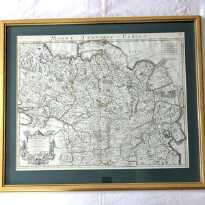 May include: Framed antique map of Tartary, featuring intricate details and text in Latin. The map is set within a gold-colored frame and a dark green mat, creating a classic aesthetic. The map's aged appearance suggests historical significance.