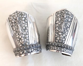 Pair of Chinese .900 silver repousse wide cuff bracelets; flowers, humans, scrolling foliage; 3 3/8 inches wide, 96.6 gms; one repair