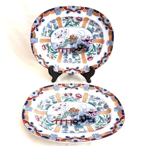 Puede incluir: Dos platos ovalados de cerámica con fondo blanco y un diseño floral colorido. Los platos presentan un borde azul, rojo y dorado con un diseño central de un puente y flores.