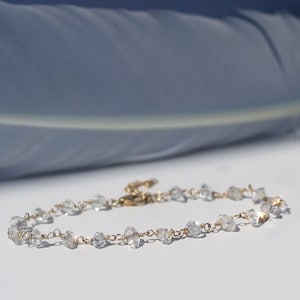 Peut inclure: Un bracelet de cheville délicat en chaîne dorée avec des perles de cristal claires et facettées.