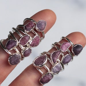 May include: Set of two silver rings with multiple stacked bands, each featuring a different shaped and sized purple gemstone.