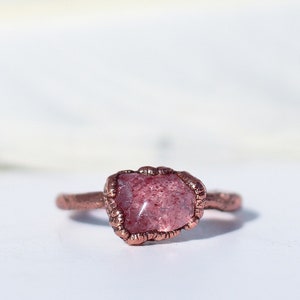 May include: A copper ring with a pink and white gemstone set in a wire-wrapped setting.
