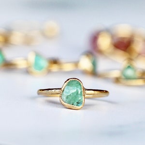 May include: A gold ring with a light green gemstone. The gemstone is a rough, irregular shape.