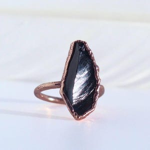 May include: A copper ring with a black, irregularly shaped stone set in the centre.