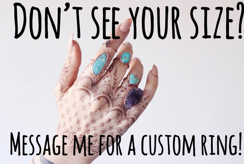 Puede incluir: Una mano con tatuajes de henna muestra varios anillos con piedras de turquesa y amatista. Los anillos tienen bandas color cobre. El texto en la parte superior dice "DON'T SEE YOUR SIZE?" y en la inferior "MESSAGE ME FOR A CUSTOM RING!"