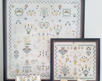 May include: A collection of cross-stitch embroidery projects featuring floral and bird motifs. The projects include a large framed piece, a smaller framed piece, and several smaller pillows. The pillows feature a variety of designs, including an alphabet, a floral pattern, and a bird pattern. The projects are all done in a muted color palette of cream, beige, and green.