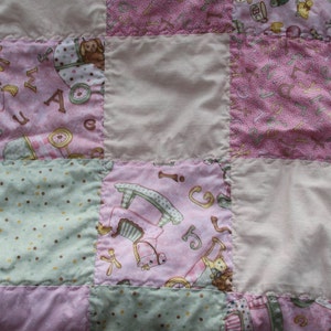Puede incluir: Una colcha de retazos rosa y verde con varios patrones y dise&ntilde;os. La colcha est&aacute; hecha de diferentes telas y tiene una textura suave y acolchada.