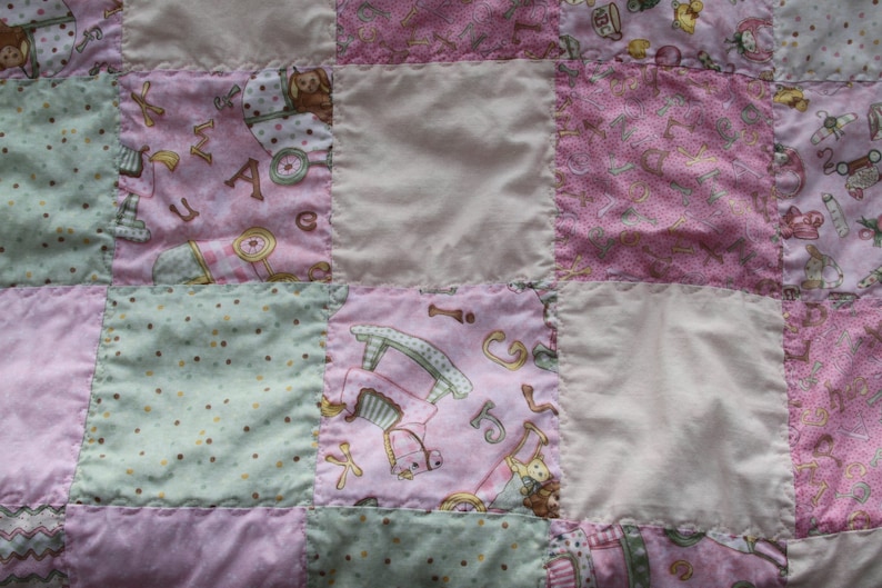 Puede incluir: Una colcha de retazos rosa y verde con varios patrones y dise&ntilde;os. La colcha est&aacute; hecha de diferentes telas y tiene una textura suave y acolchada.