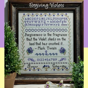 May include: A framed cross-stitch design with the quote "Forgiveness is the fragrance that the Violet sheds on the heel that has crushed it. - Mark Twain". The design includes a purple alphabet, numbers, and the words "Peace" and "Charity".