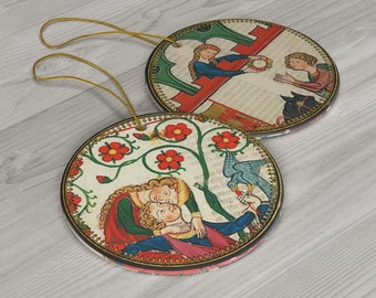 May include: Two round ceramic ornaments with a gold string for hanging. The ornaments feature medieval-style illustrations of couples in romantic scenes. One ornament depicts a couple in a garden with red flowers and a bird. The other ornament shows a couple exchanging a wreath through a window.