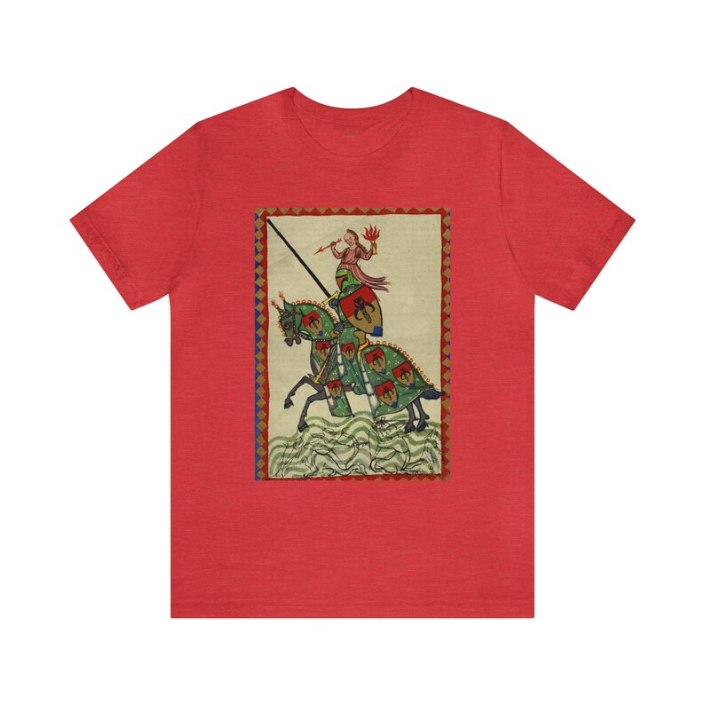 May include: Red t-shirt featuring a medieval illustration of a knight on horseback. The artwork depicts a knight in armor with a lance, riding a green horse with red and green accents. The background is a cream color with a decorative border.