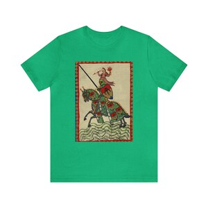 May include: Green t-shirt featuring a medieval illustration of a knight on horseback. The artwork depicts a knight in armor with a spear, riding a horse with green and red accents. The background is a cream color with a red border.