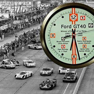 Op de afbeelding: Een vintage-stijl klok met een groene wijzerplaat en gouden rand. De klok heeft de tekst "Ford GT40" en een lijst met coureurs en jaren van overwinningen in de 24 uur van Le Mans.