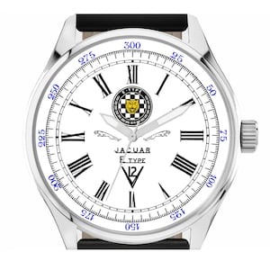 May include: A silver wristwatch with a white face featuring black Roman numerals and blue markings. The watch has a black leather band and a Jaguar logo. The text "JAGUAR F-TYPE" is printed on the watch face.