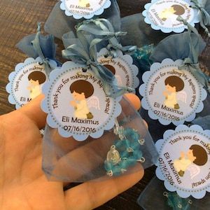 May include: Blue and white favor bags with blue and silver rosary beads and a thank you tag that reads "Thank you for making My Baptism special Eli Maximus 07/16/2016".