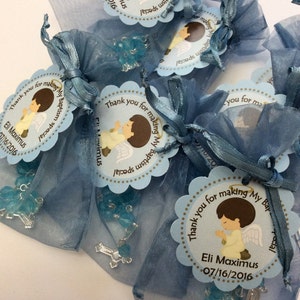 May include: Blue organza bags filled with blue and silver rosary beads and a thank you tag with a cartoon angel and the text "Thank you for making my baptism special Eli Maximus 07/16/2016".