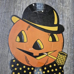 May include: A vintage cardboard cutout of a jack-o'-lantern wearing a black bowler hat with a yellow band and a black bowtie with yellow polka dots. The pumpkin face features yellow eyes, a nose, and a mouth holding a yellow corn cob pipe.