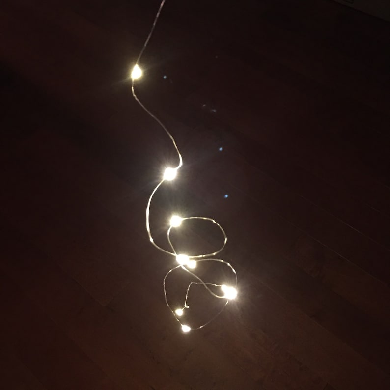 May include: A string of white fairy lights with a warm glow, hanging from the ceiling and forming a heart shape.