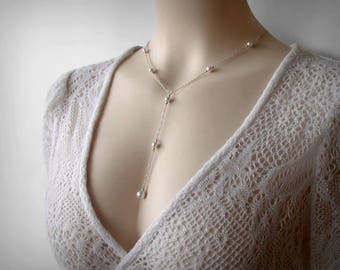 Può includere: Una collana d'argento con piccole perle rotonde. La collana ha un design a forma di Y con una catena più lunga che si estende dal centro della Y.
