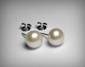 Puede incluir: Un par de pendientes de perlas con postes y respaldos de plata. Las perlas son blancas y redondas.