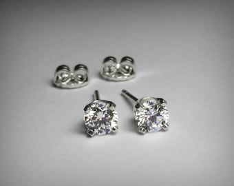 Puede incluir: Un par de pendientes de plata con piedras redondas de circonita cúbica transparentes.