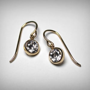 May include: A pair of gold earrings with clear round stones.