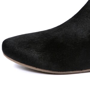 May include: Close-up of a black boot with a textured, fur-like appearance. The boot has a rounded toe and a light brown sole. The focus is on the front portion of the shoe.