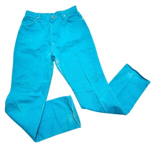 May include: Bright turquoise denim jeans. The jeans have a high waist and a classic five-pocket design. The pants are made of a sturdy denim material and have a slight flare at the bottom. The jeans are a vibrant color and appear to be vintage.