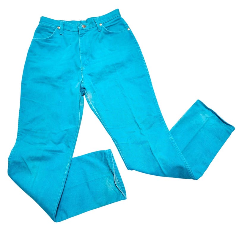 May include: Bright turquoise denim jeans. The jeans have a high waist and a classic five-pocket design. The pants are made of a sturdy denim material and have a slight flare at the bottom. The jeans are a vibrant color and appear to be vintage.