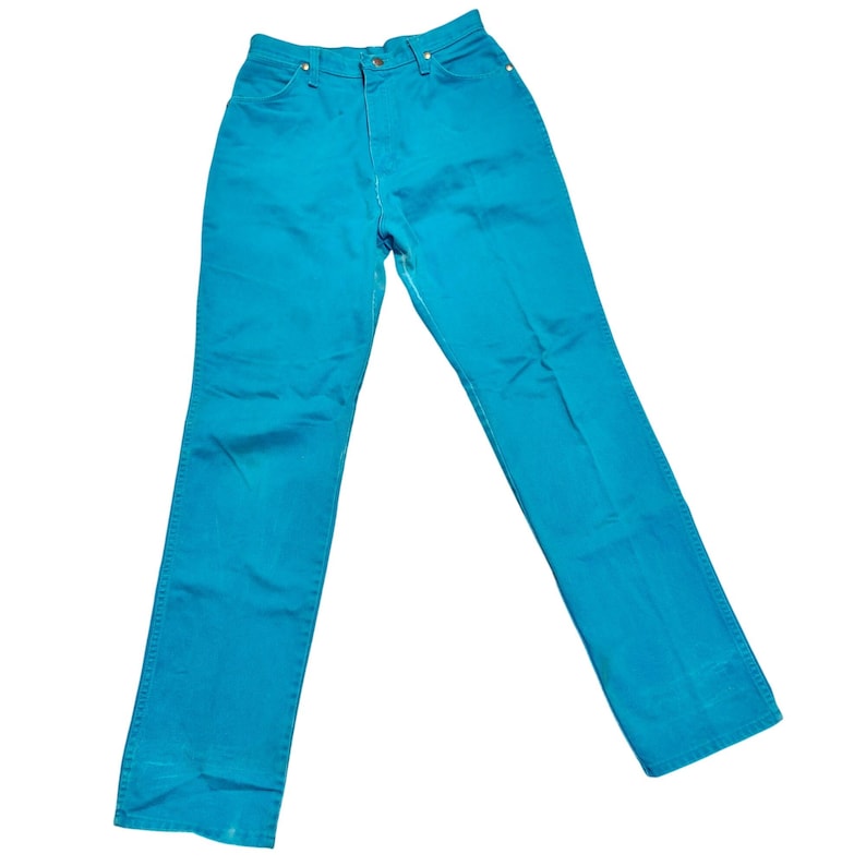 May include: A pair of turquoise denim jeans. The jeans have a classic five-pocket design, a button and zipper closure, and white stitching. The pants are a solid color and appear to be made of a sturdy denim material.