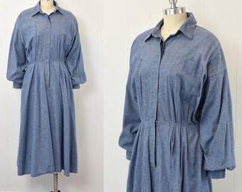 May include: A long-sleeved denim dress with a collared neckline, button closure, and a gathered waist. The dress has a relaxed fit and a midi length.